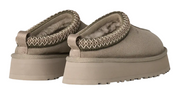 Pair of beige slippers with textured straps on a white background