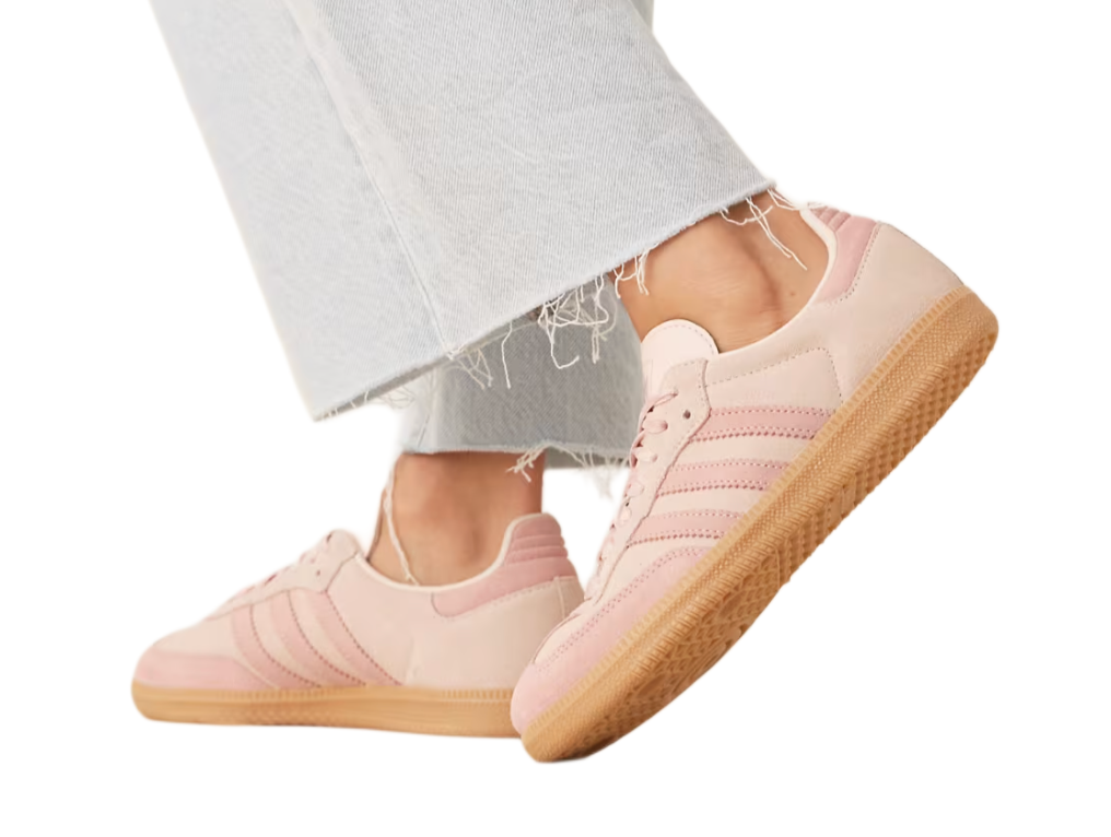 Pink sneakers with light brown soles worn with light gray pants on a white background